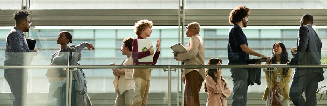 Business colleagues standing and talking in a bright, modern building corridor